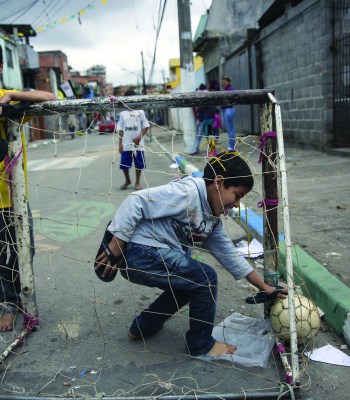 SAO PAULO, BRAZIL - JUNE 21:  Children play football in the street in the poor neighbourhood of Itaquera, adjacent to the 'Arena de Sao Paulo' stadium, on June 21, 2014 in Sao Paulo, Brazil. The Arena de Sao Paulo, which is reported to have cost in excess of 200 million GBP, hosted the opening match of the 2014 FIFA World Cup and has a capacity of over 61,000. The total cost borne by Brazil for staging the 2014 World Cup is estimated to be 6.5 billion GBP, which critics have argued would have better spent on the millions of Brazilians living in poverty.  (Photo by Oli Scarff/Getty Images)